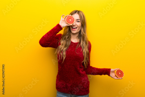 Young woman holding orange slices on vibrant yellow background