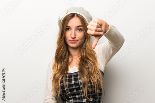 Fashionably woman wearing hat showing thumb down sign with negative expression