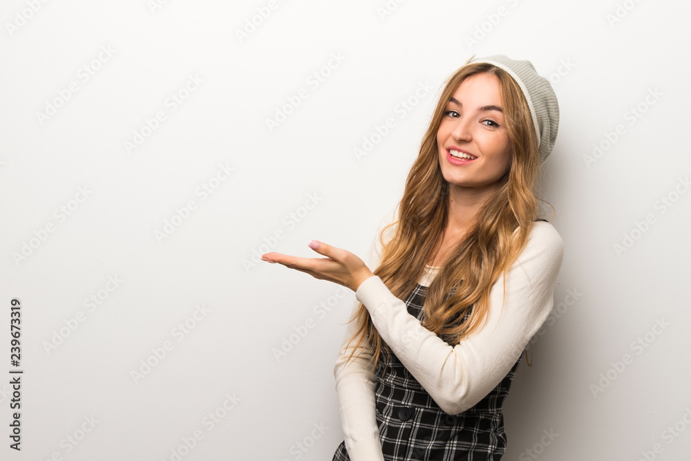 Fashionably woman wearing hat presenting an idea while looking smiling towards