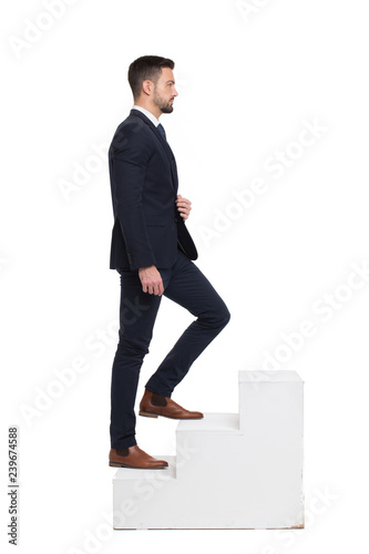 Stylish caucasian businessman walking up on steps isolated