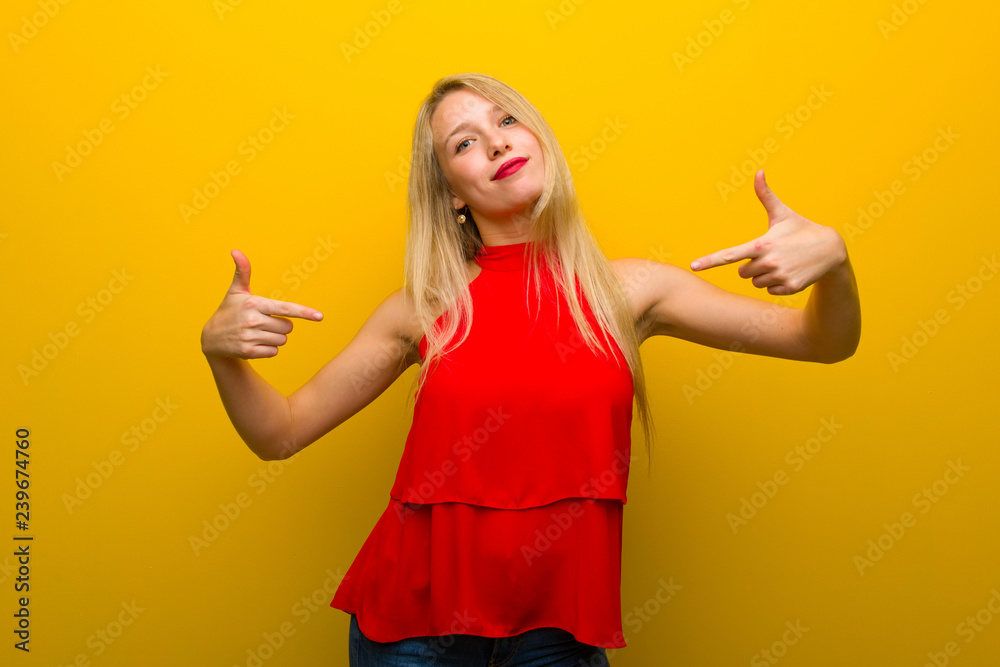 Young girl with red dress over yellow wall proud and self-satisfied in love yourself concept Young girl with red dress over yellow wall proud and self-satisfied in love yourself concept