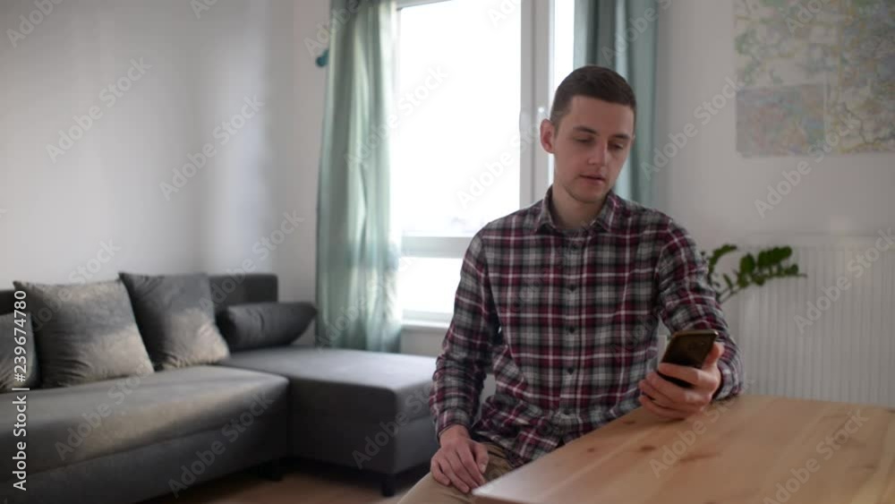 A Young Man at Home use Mobile Smart Phone chatting with Friends A Young Man at Home use Mobile Smart Phone chatting with Friends