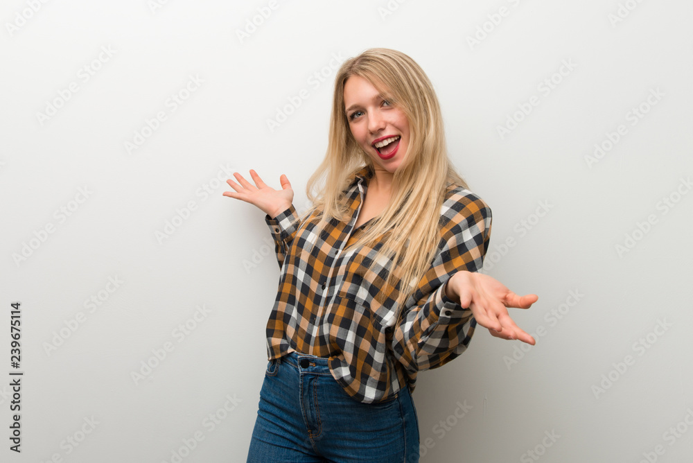 Blonde young girl over white wall proud and self-satisfied in love yourself concept Blonde young girl over white wall proud and self-satisfied in love yourself concept