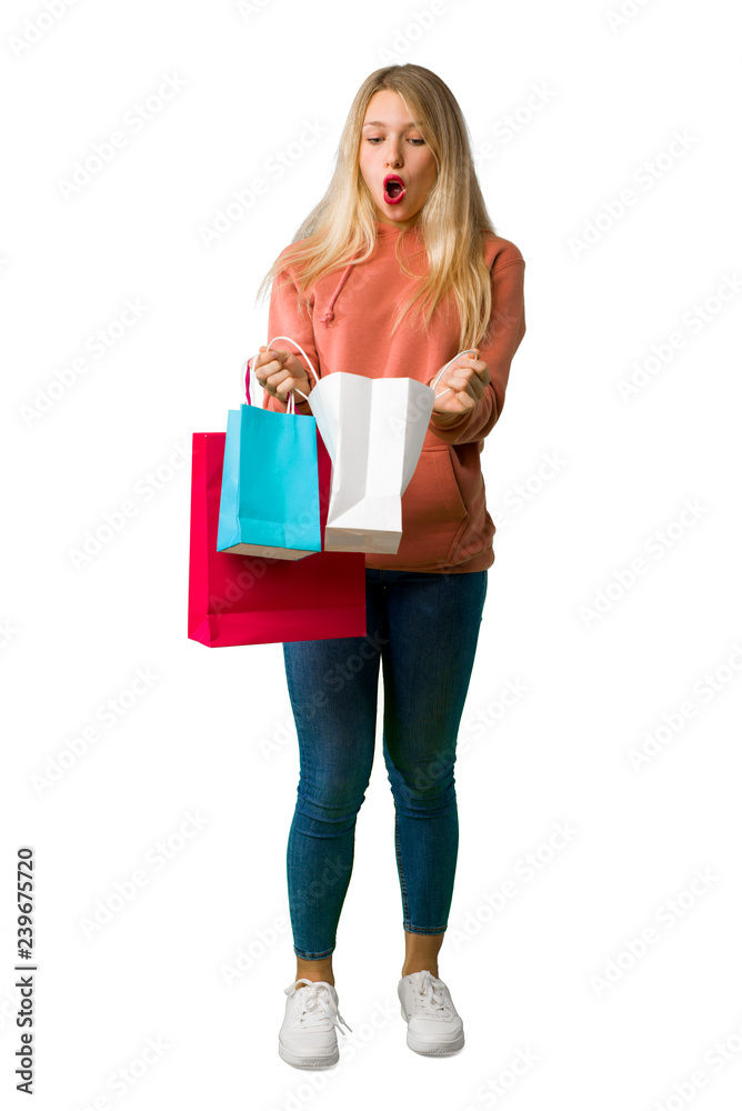 A full-length shot of a Young girl surprised while holding a lot of shopping bags on isolated white background A full-length shot of a Young girl surprised while holding a lot of shopping bags on isolated white background