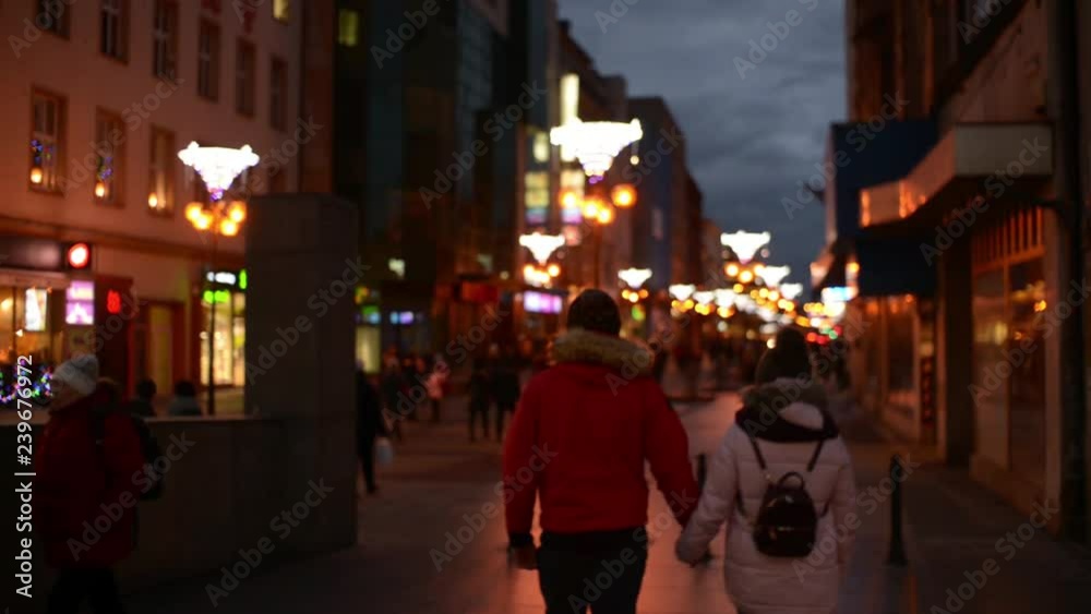 Young Man and Woman Lovers walking along the Night Christmas Street in the City Young Man and Woman Lovers walking along the Night Christmas Street in the City