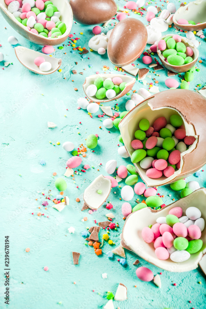 Colorful spring easter sweets background, with chocolate eggs, sugar sprinkles and marshmallow bunny, turquoise light blue concrete background copy space top view