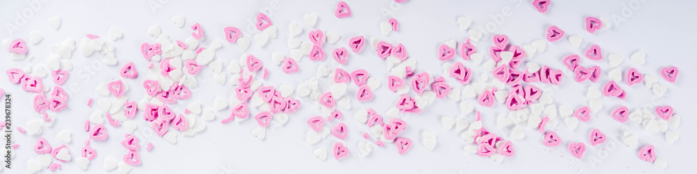 Valentine's sweets background, white background with sugar hearts sweet sprinkles, copy space top view, layout on white banner