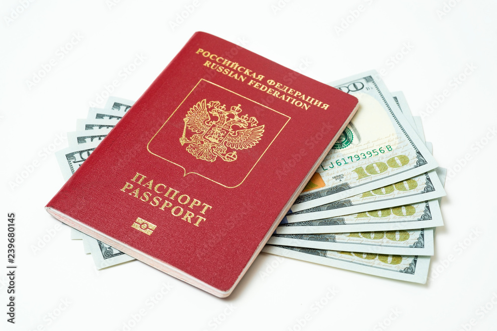 Biometric travel passport of the Russian Federation with dollars isolated on white background. Five bills for a hundred dollars. The concept of tourism. The concept of investment. Closeup. Biometric travel passport of the Russian Federation with dollars isolated on white background. Five bills for a hundred dollars. The concept of tourism. The concept of investment. Closeup.