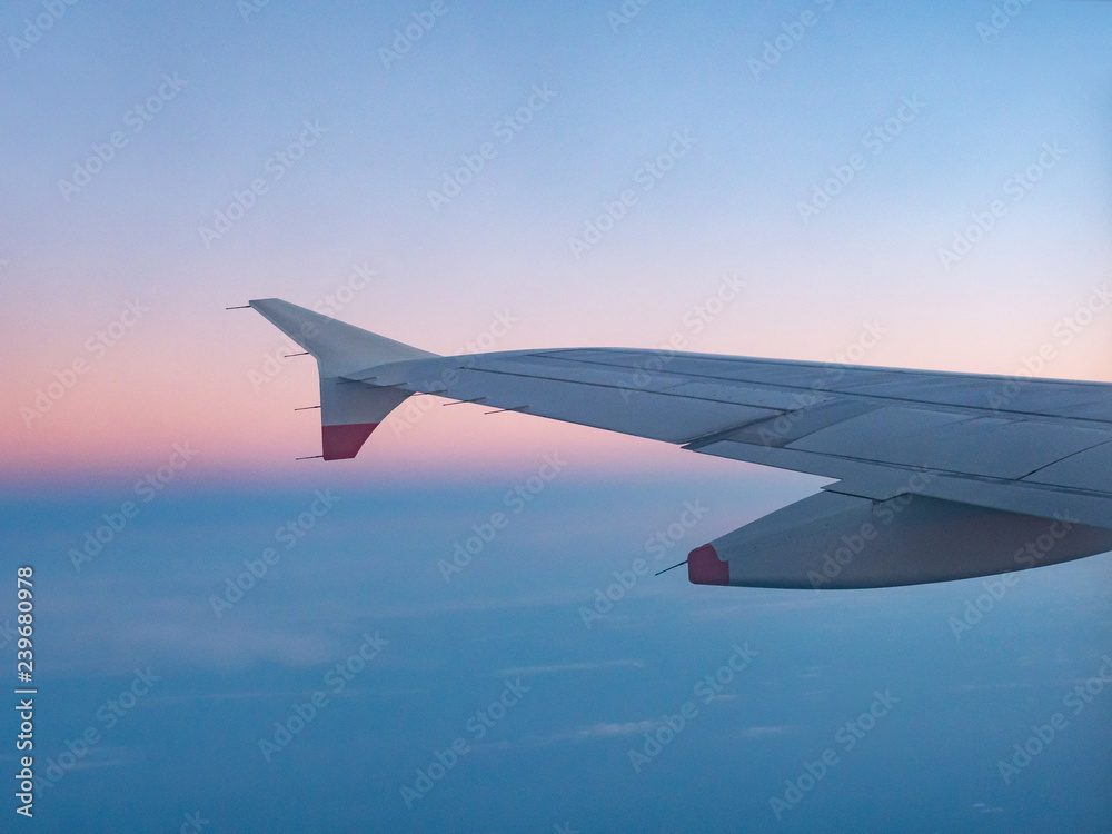 Wing of an airplane flying above the morning clouds Wing of an airplane flying above the morning clouds