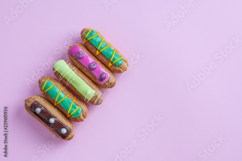 Top view of decorative French eclairs on pink background with copy space