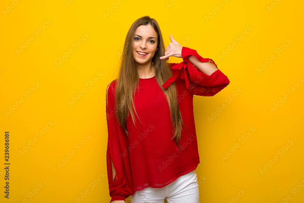 Young girl with red dress over yellow wall making phone gesture. Call me back sign Young girl with red dress over yellow wall making phone gesture. Call me back sign