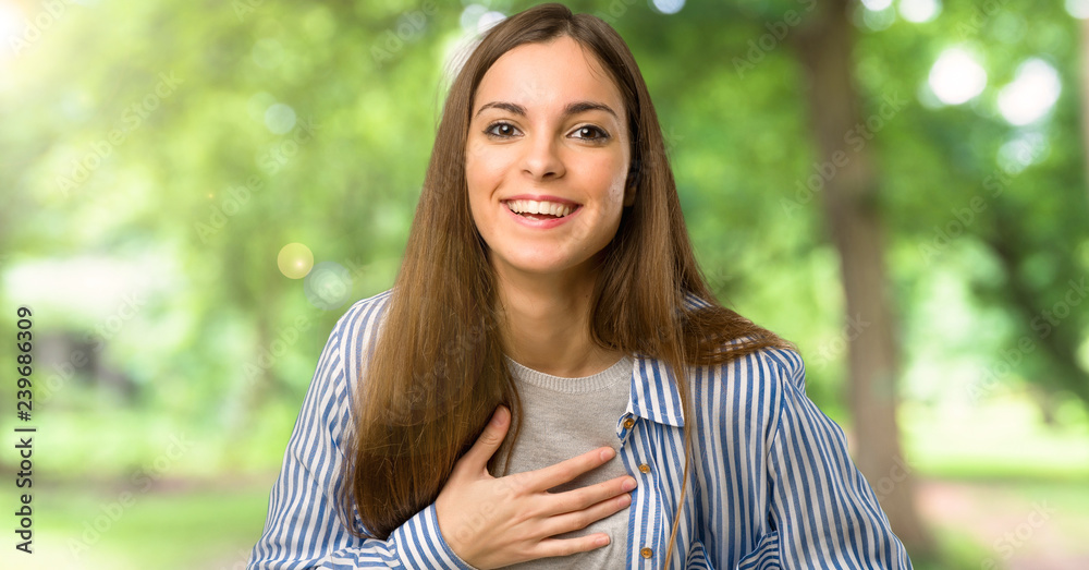 Young girl with striped shirt smiling a lot while putting hands on chest at outdoors Young girl with striped shirt smiling a lot while putting hands on chest at outdoors