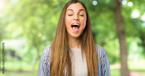 Young girl with striped shirt shouting to the front with mouth wide open at outdoors