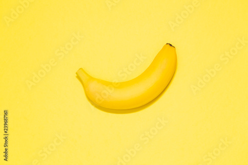 Single banana on a yellow background. Top view. Room for text. Minimalist concept.