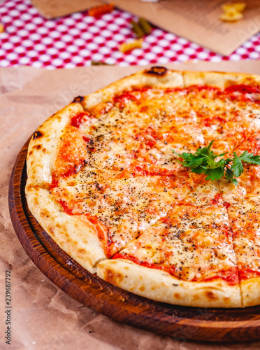 Italian Pizza Margherita with tomatoes and mozzarella cheese on wooden cutting board. Close up