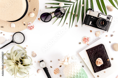 Traveler accessories on white background with retro camera, straw hat, sunglasses and tropical palm leaf. Essential vacation items, Travel concept background. Top view