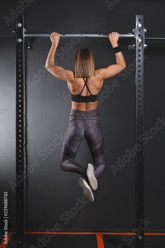 Woman athlete executing pull up in gym © BigBlueStudio
