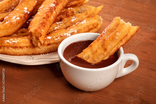 Traditional Spanish porras dipped in hot chocolate, a typical Madrid Sunday breakfast, on a dark rustic wooden background with copy space photo