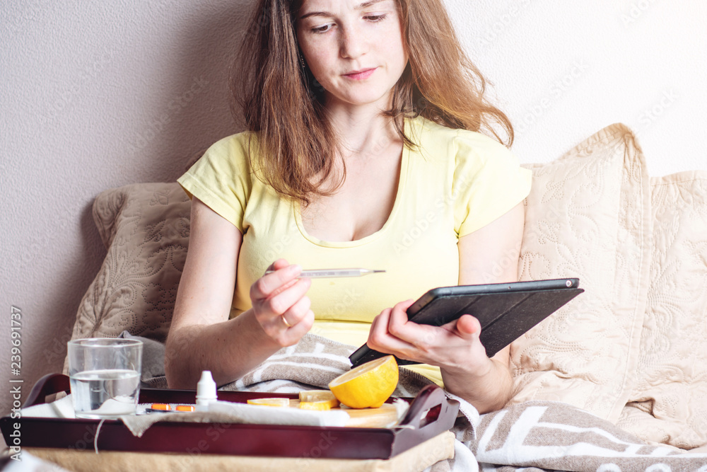 Girl with a headache and flu in bed is treated with tablets and vitamins. Seasonal colds in winter