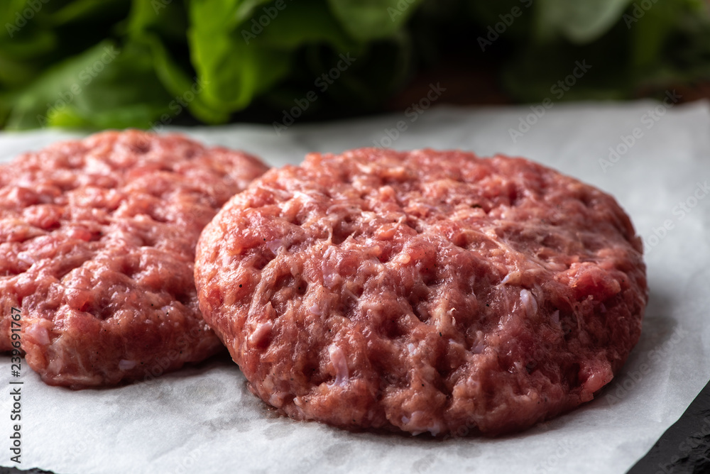 Raw burger patties on white paper, raw minced pork. Raw burger patties on white paper, raw minced pork.