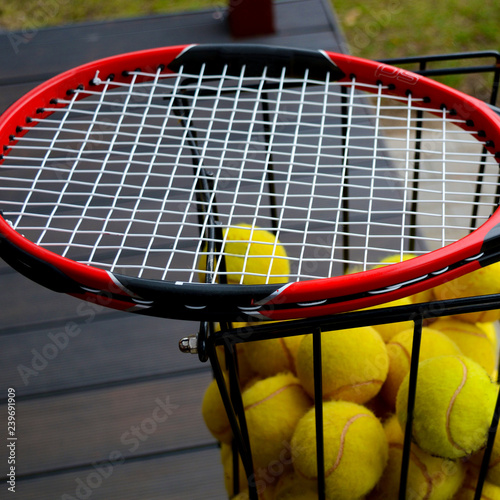 close up view of yellow tennis balls in basket with racquet © Romo Lomo