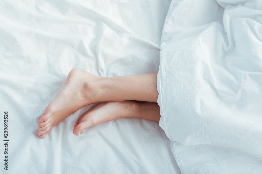 low section of female legs under blanket in bed low section of female legs under blanket in bed