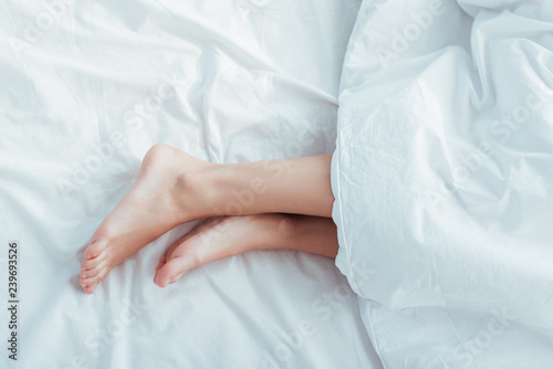 low section of female legs under blanket in bed