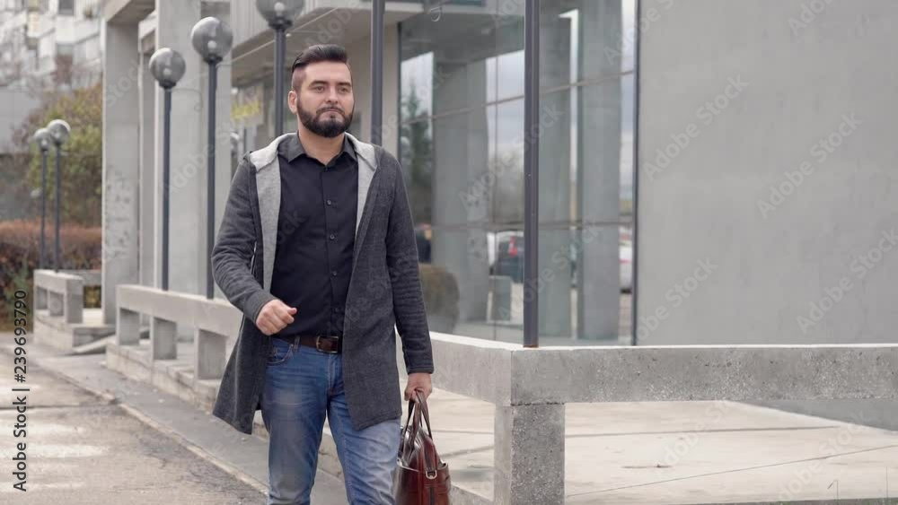 confident adult man is wearing casual style and carrying handbag is strolling on city street in autumn day confident adult man is wearing casual style and carrying handbag is strolling on city street in autumn day
