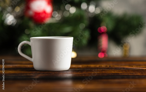 Cup of coffee or tea on a wooden table against the background of a Christmas tree