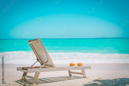 two coconut drinks and chair on tropical beach