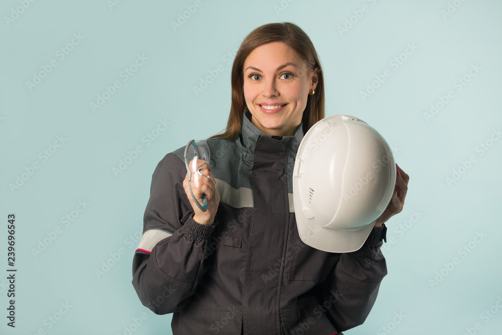 beautiful young girl in overalls holding a hard hat