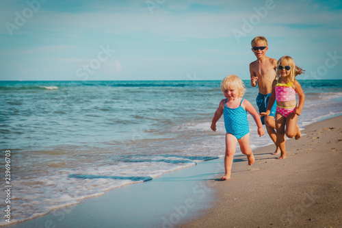 happy kids -little boy and girls- run play at beach