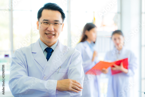  A middle aged man scientist smiling happily with his arms crossed posing at her laboratory colleagues. A confident professor CEO standing preparing equipment for teaching collage student. Copy space.