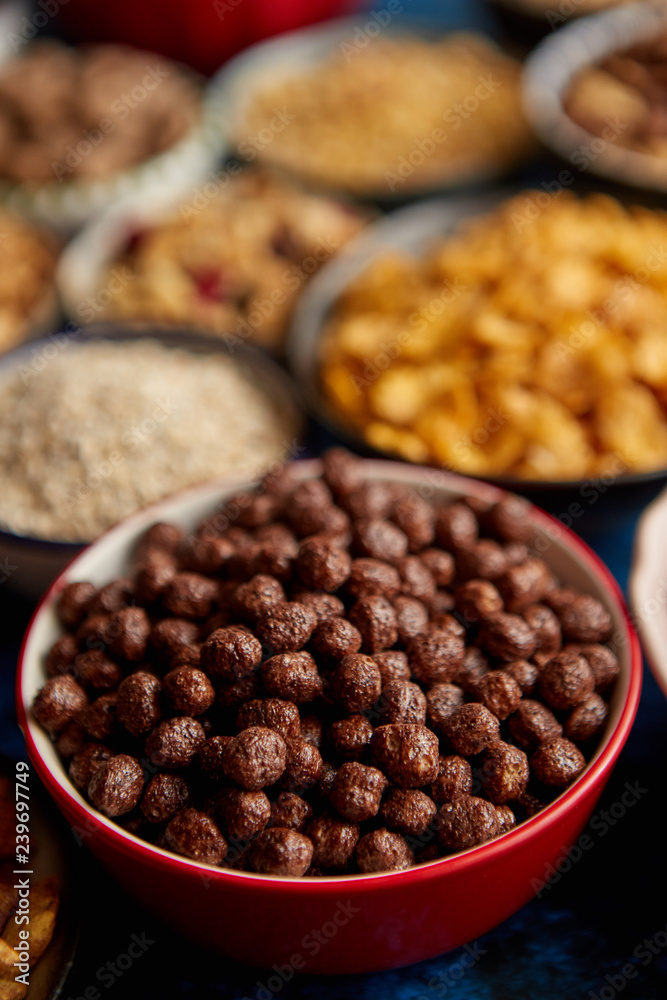 Assortment of various kinds cereals placed in ceramic bowls with cornflakes, granola, cereals and oatmeal. Flat lay, top view on blue rusty table with copy space in the middle. Selective focus. Assortment of various kinds cereals placed in ceramic bowls with cornflakes, granola, cereals and oatmeal. Flat lay, top view on blue rusty table with copy space in the middle. Selective focus.