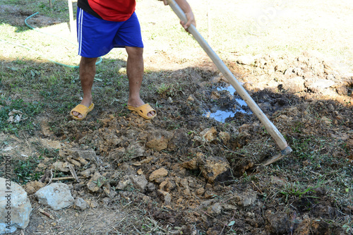 unsafe working . A labor digging the ground with spade in construction site with out safety shoes and uniform