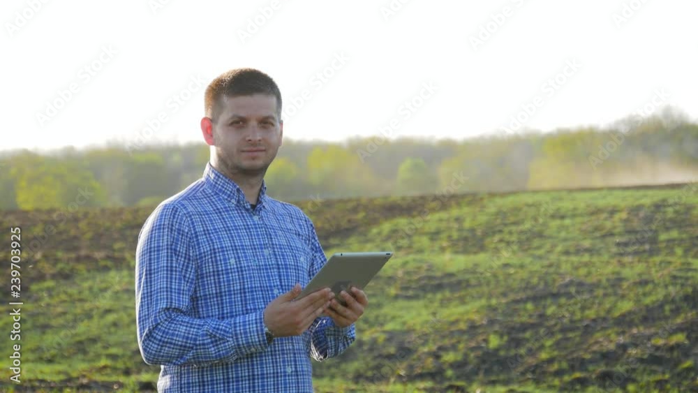 Portrait of young farmer with tablet computer standing in field. Concept farmers, food, bio product. Portrait of young farmer with tablet computer standing in field. Concept farmers, food, bio product.