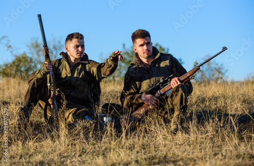 Hunting with friends hobby leisure. Rest for real men concept. Discussing catch. Hunters with rifles relaxing in nature environment. Hunter friend enjoy leisure in field. Hunters gamekeepers relaxing