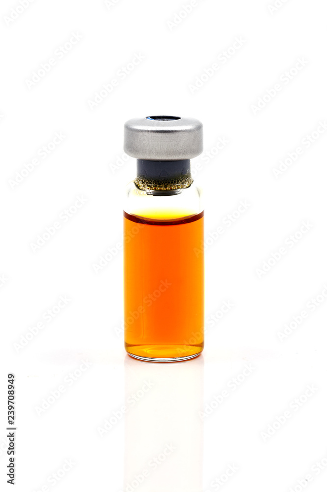 Glass vial medical with orange colored vaccine on isolated white background.