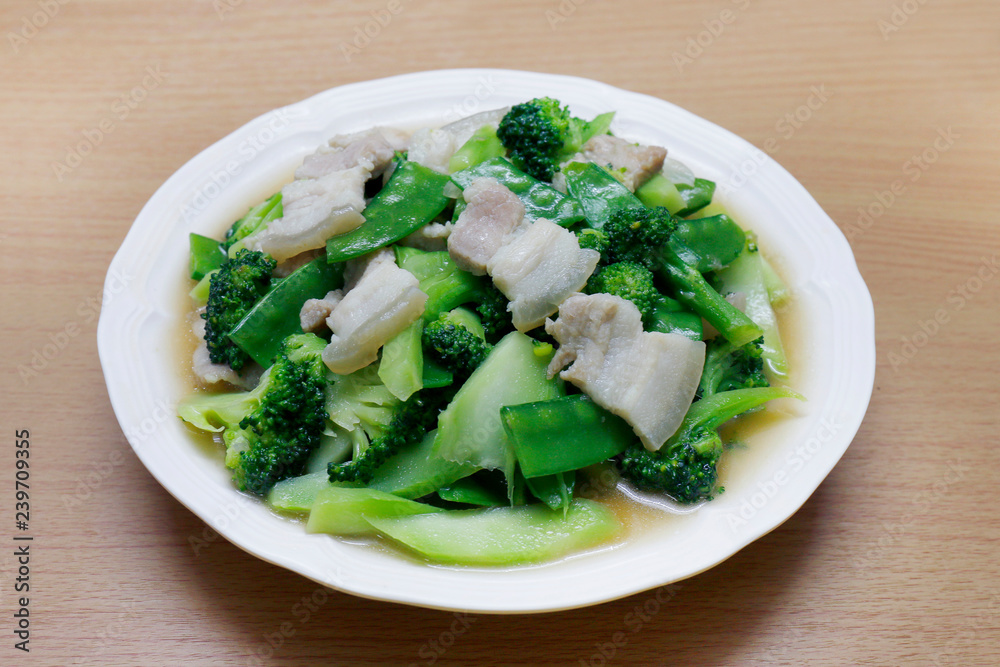 Stir Fried Broccoli, Peas with Crispy Pork with oyster sauce, Fried vegetable broccoli for food menu diet healthy in a dish on a wooden floor (Thai Foods) Stir Fried Broccoli, Peas with Crispy Pork with oyster sauce, Fried vegetable broccoli for food menu diet healthy in a dish on a wooden floor (Thai Foods)
