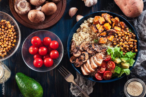 Vegetable buddha bowl lunch with chicken and quinoa, chickpea, mushrooms, lettuce and tomatoes