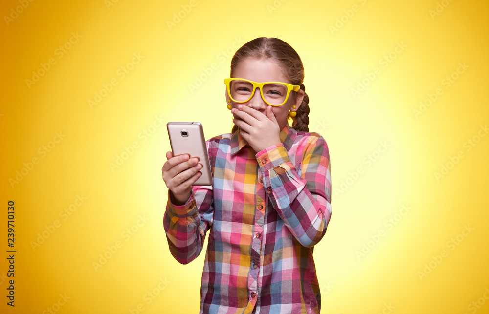 Emotional teen girl with mobile phone on yellow background Emotional teen girl with mobile phone on yellow background