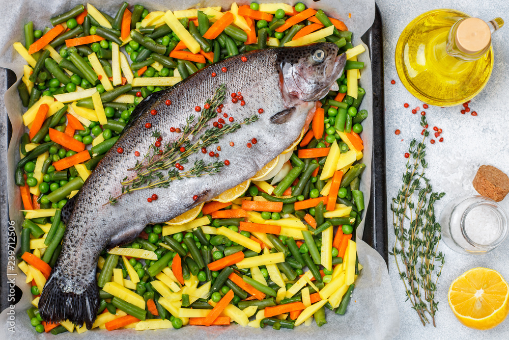 Raw fish trout with vegetables (potatoes, carrots, string beans, green peas and onions) is ready for baking with lemon, thyme and pink pepper. Wild salmon. Healthy Diet.  Selective focus