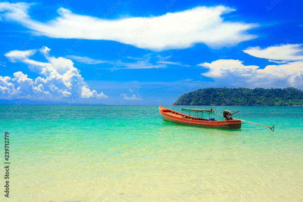 A fishing boat floating on beach with clean and clear sea and cloudy blue sky. Copy space.	