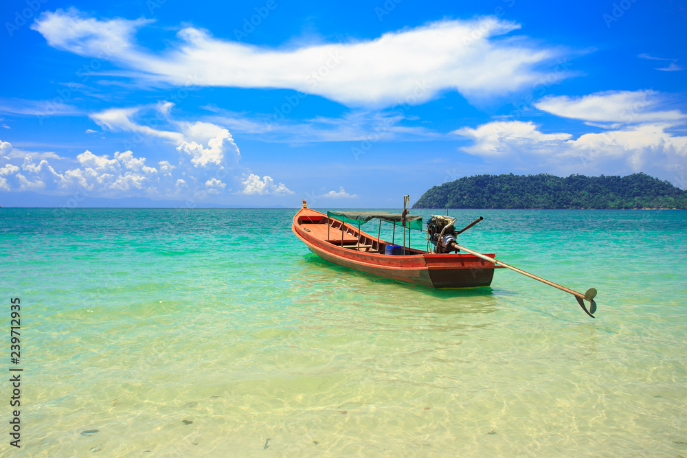 A fishing boat floating on beach with clean and clear sea and cloudy blue sky. Copy space. A fishing boat floating on beach with clean and clear sea and cloudy blue sky. Copy space.