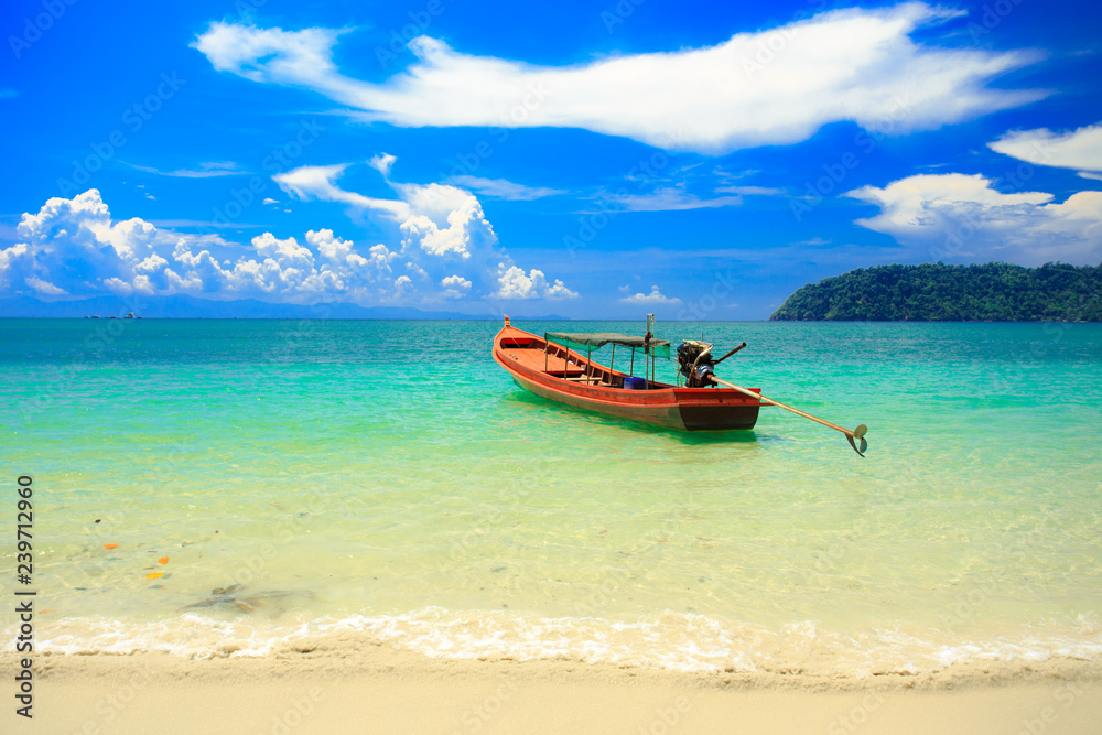 A fishing boat floating on beach with clean and clear sea and cloudy blue sky. Copy space.