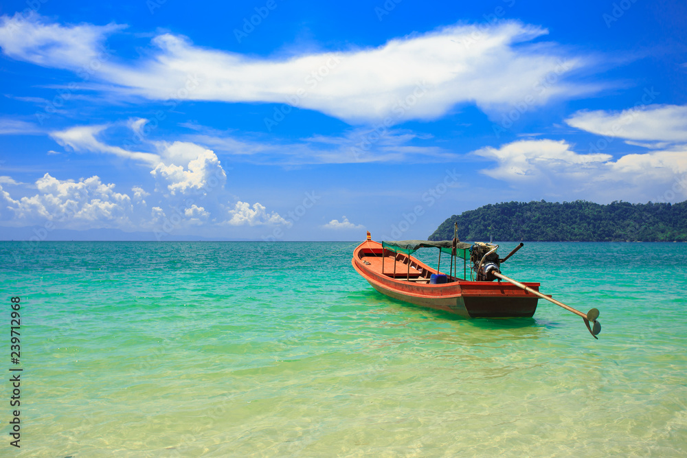 A fishing boat floating on beach with clean and clear sea and cloudy blue sky. Copy space. A fishing boat floating on beach with clean and clear sea and cloudy blue sky. Copy space.