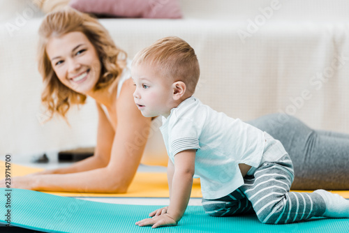 woman lying on carpet and smiling to adorable boy