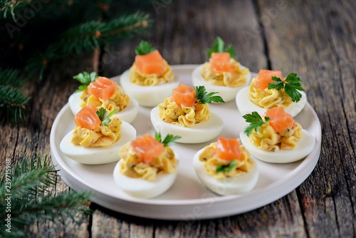 Stuffed chicken eggs with soft cheese, capers and salted salmon. Christmas background.