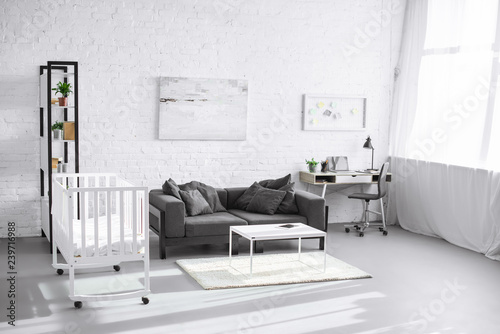 Fototapeta Naklejka Na Ścianę i Meble -  modern interior of living room with baby crib, sofa and workplace