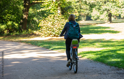 Healthy lifestyle. Woman is riding a bike in a path of Tiergarten park, Berlin, Germany. Nature background.